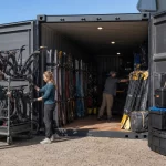Denver outdoor recreation staff organizing skis bikes and paddles in a high-cube container