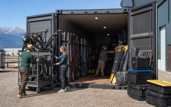 Denver outdoor recreation staff organizing skis bikes and paddles in a high-cube container