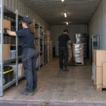 Worker retrieving organized inventory from shelving inside a shipping container