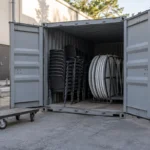 Stackable chairs and folded tables stored in an open container at a venue courtyard